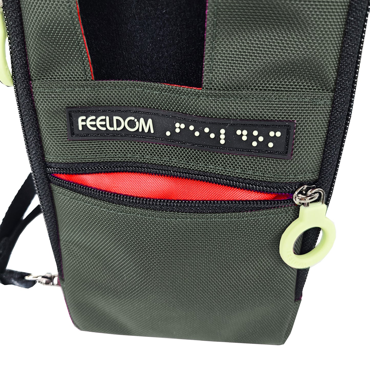 Close up of the front zipper pocket and white ring pull on the Navi Pal pouch. It is open to show the bright lining. The small pocket is enough to put a business card or earbuds or small objects into. The Braille FEELDOM logo tag is right above the zipper.