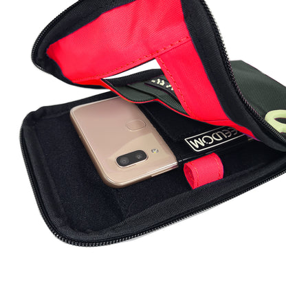 Open view of the Dark Gray Navi Pal pouch showing a flourescent red lining. The smartphone is secured into the holster, which is positioned along the center of the back of the pouch. There is a brightly colored pen loop along the inner edge.